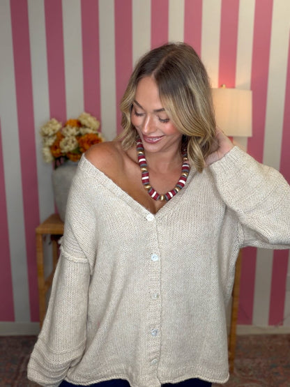 woman standing in a room in a beige sweater