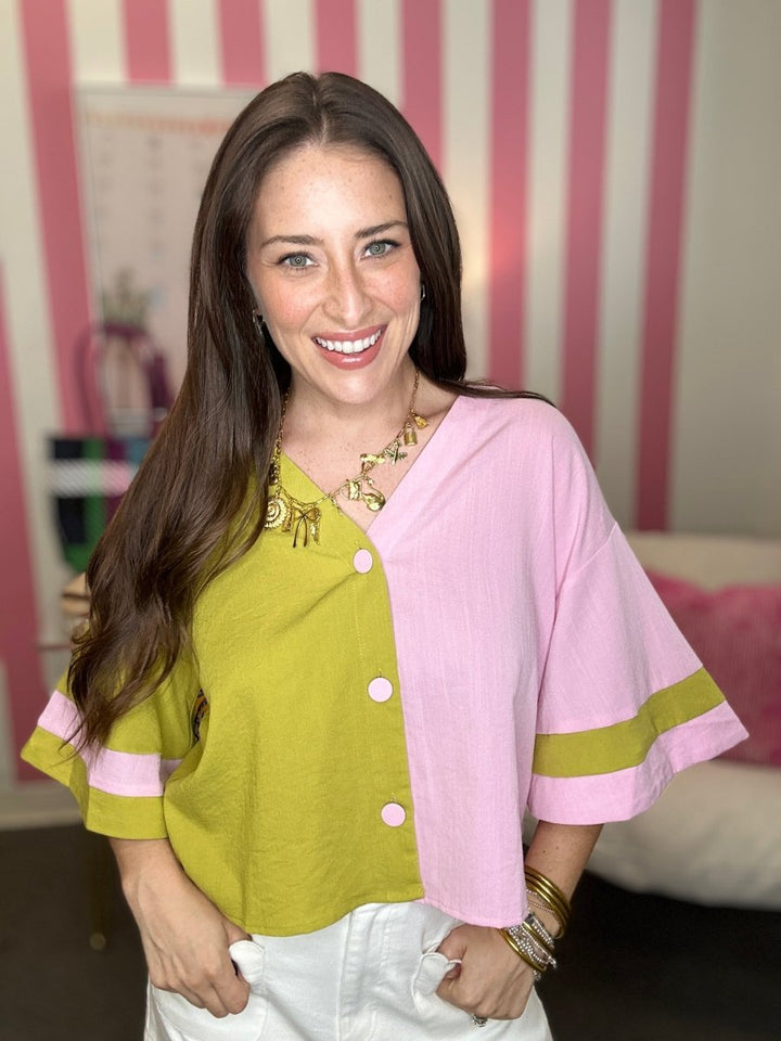 Woman wearing a green top with pink accents and a pink shawl indoors.