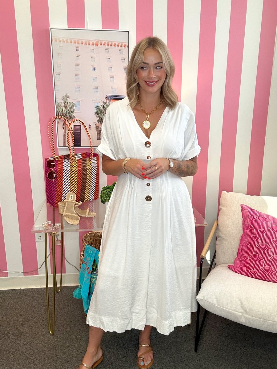 Woman in a white dress standing in a room with pink and white striped walls.