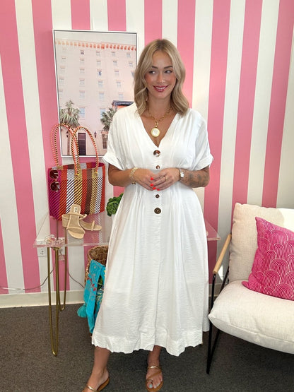 Woman in a white dress standing in a room with pink and white striped walls.