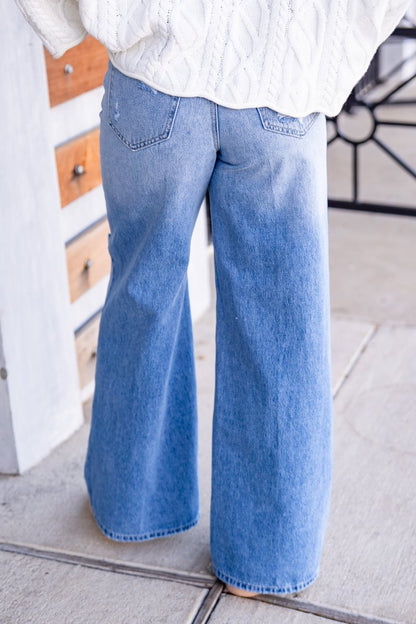 Person wearing blue jeans and a white shirt indoors.