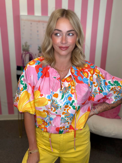 Person wearing a colorful shirt with a striped wall in the background