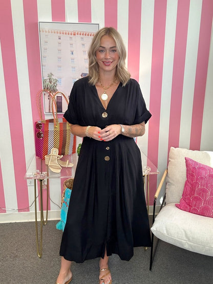 Woman in a black dress standing in a room with pink and white striped walls.