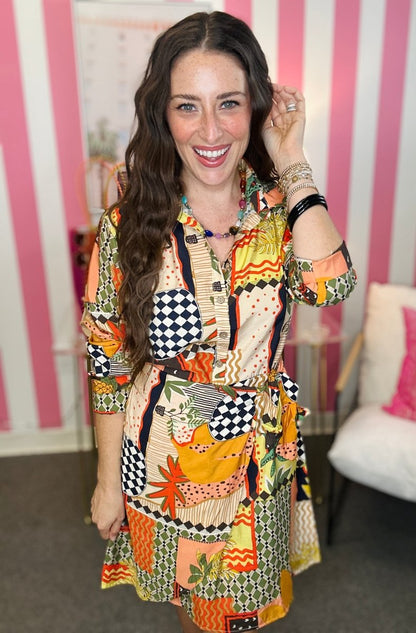 Woman wearing a colorful patterned dress in an indoor setting with pink and white striped walls.