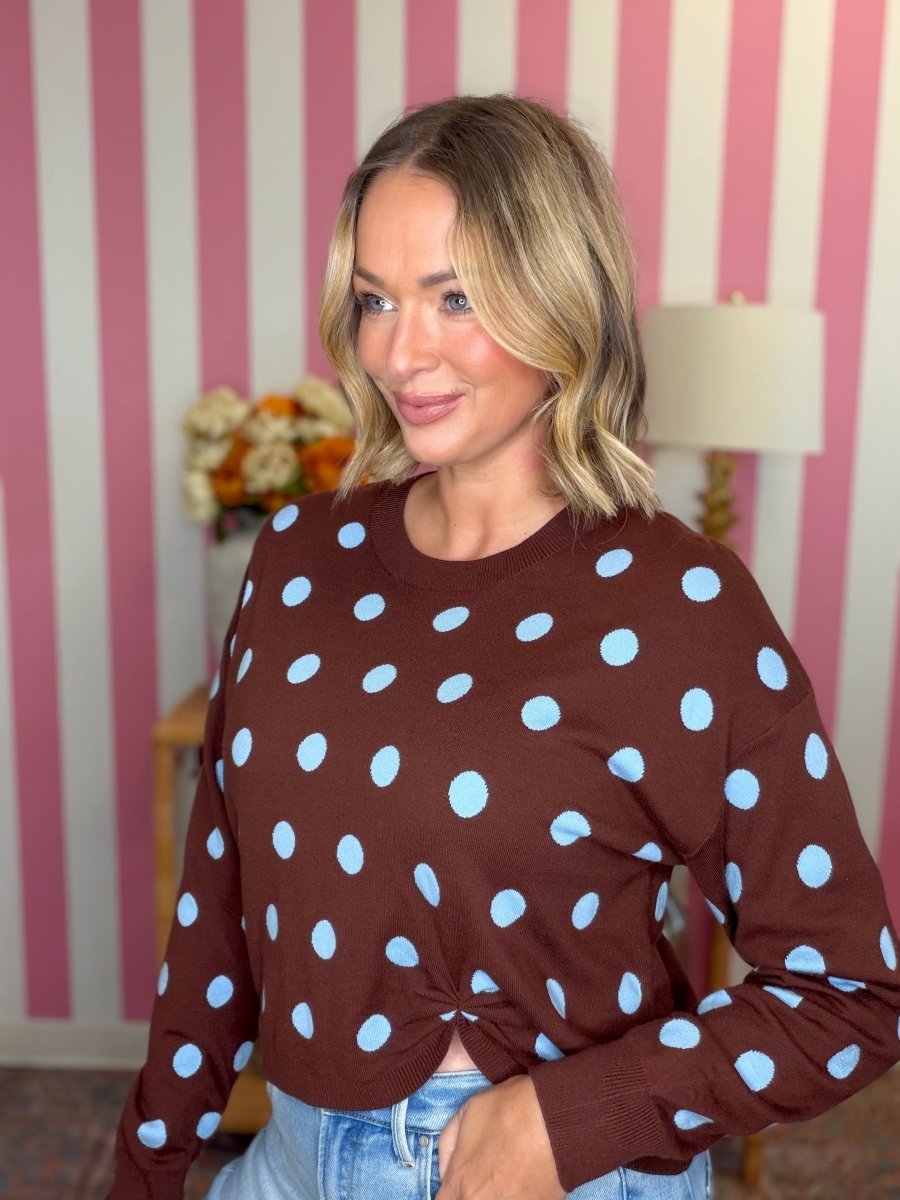 woman standing in brown sweater with blue polka dots