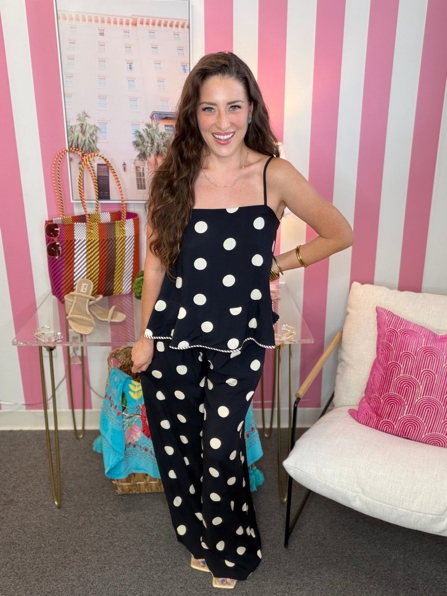 Woman in a polka dot outfit standing in a room with striped walls and furniture.