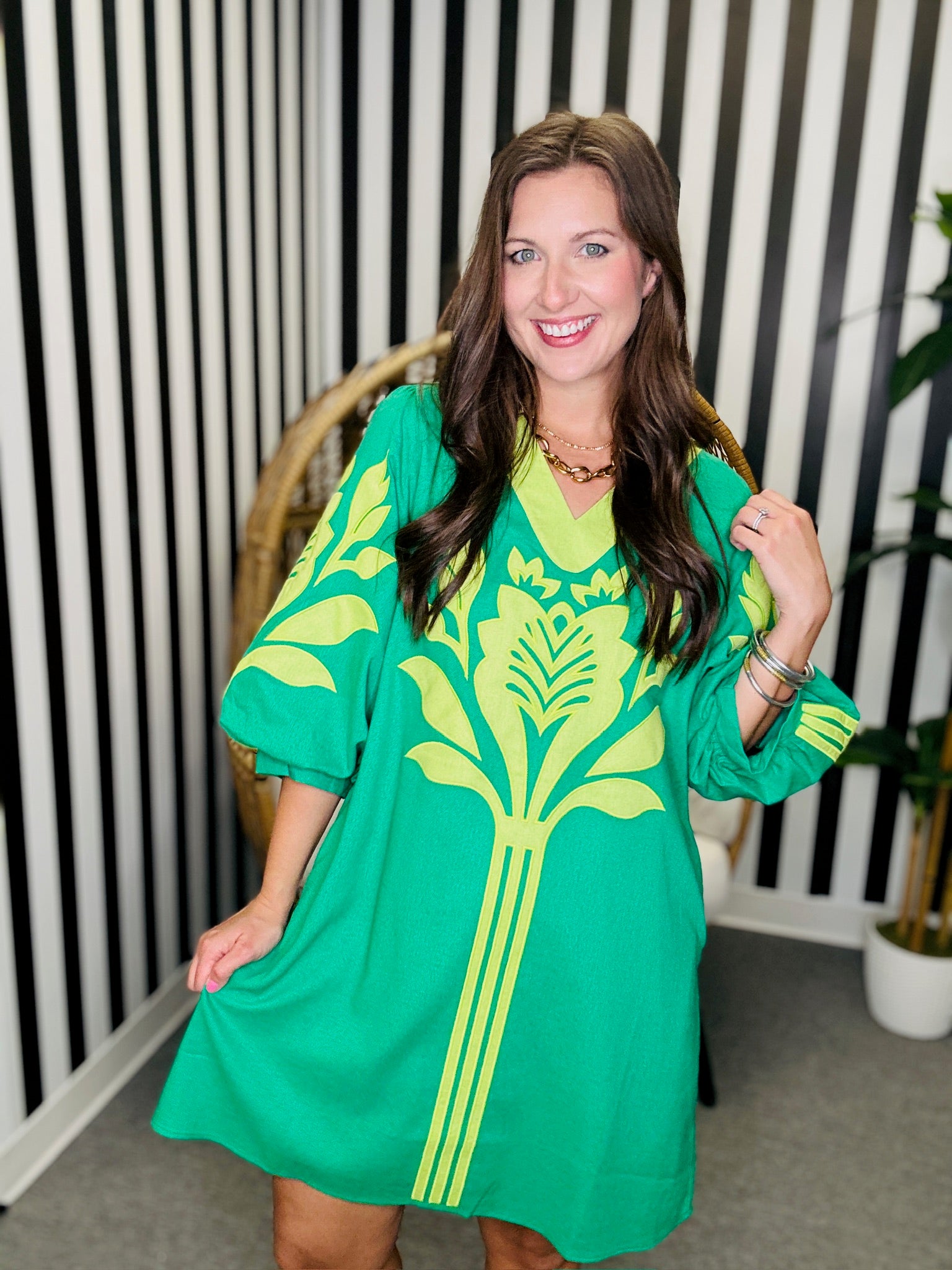 Woman wearing a green dress with yellow patterns indoors.