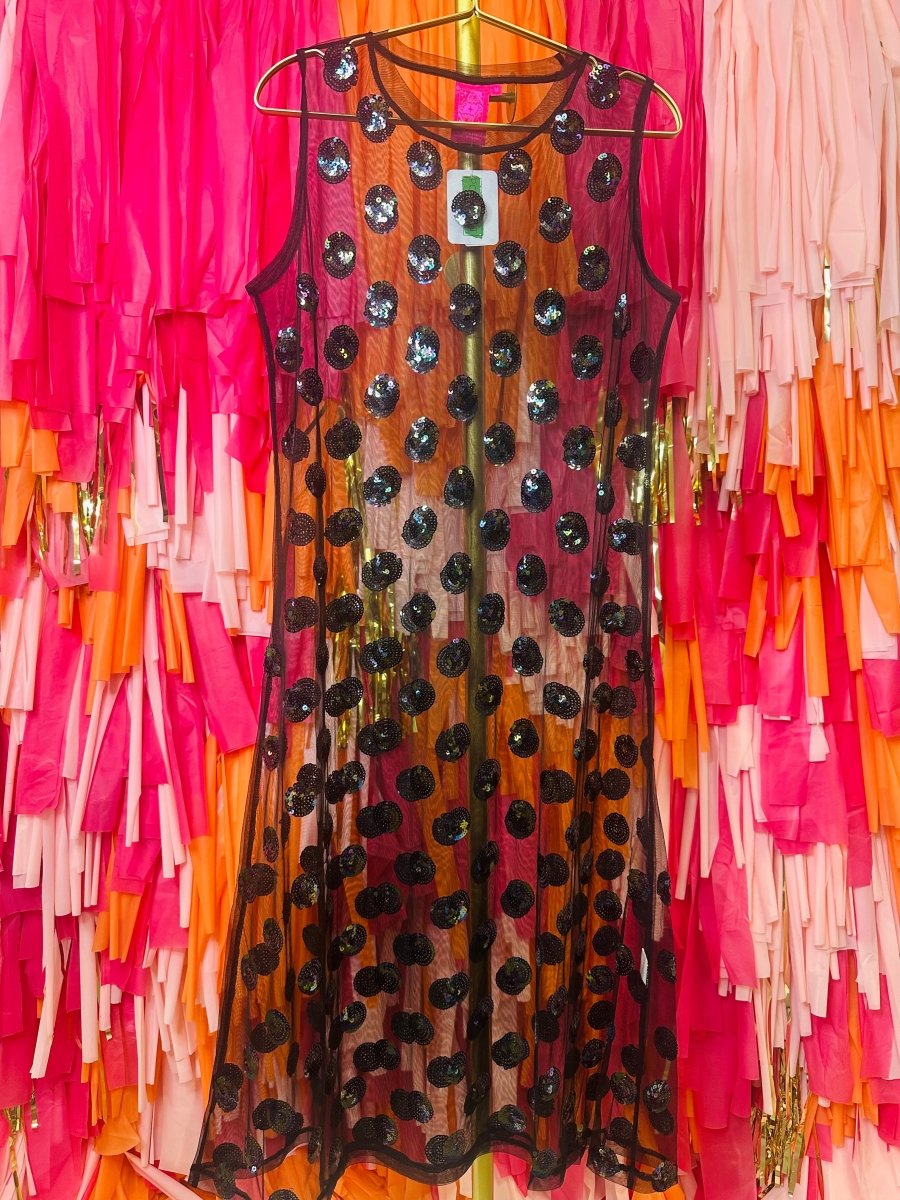 Dress with black polka dots on a hanger against a colorful fringe background