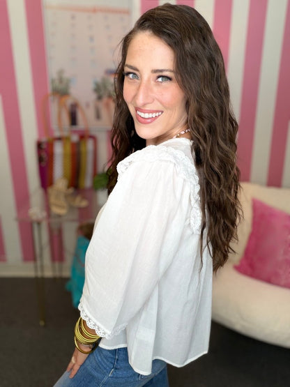 Woman wearing a white blouse with a striped wall and sofa in the background