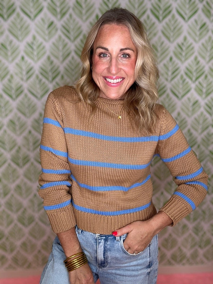 woman standing in room in striped sweater and jeans