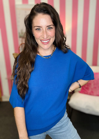 Woman wearing a blue top and jeans with a striped pink and white background