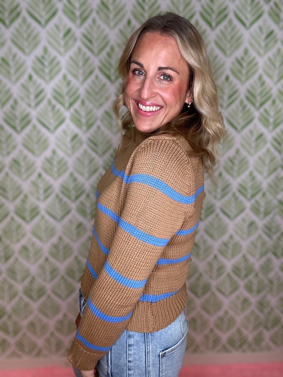 woman standing in room in striped sweater and jeans