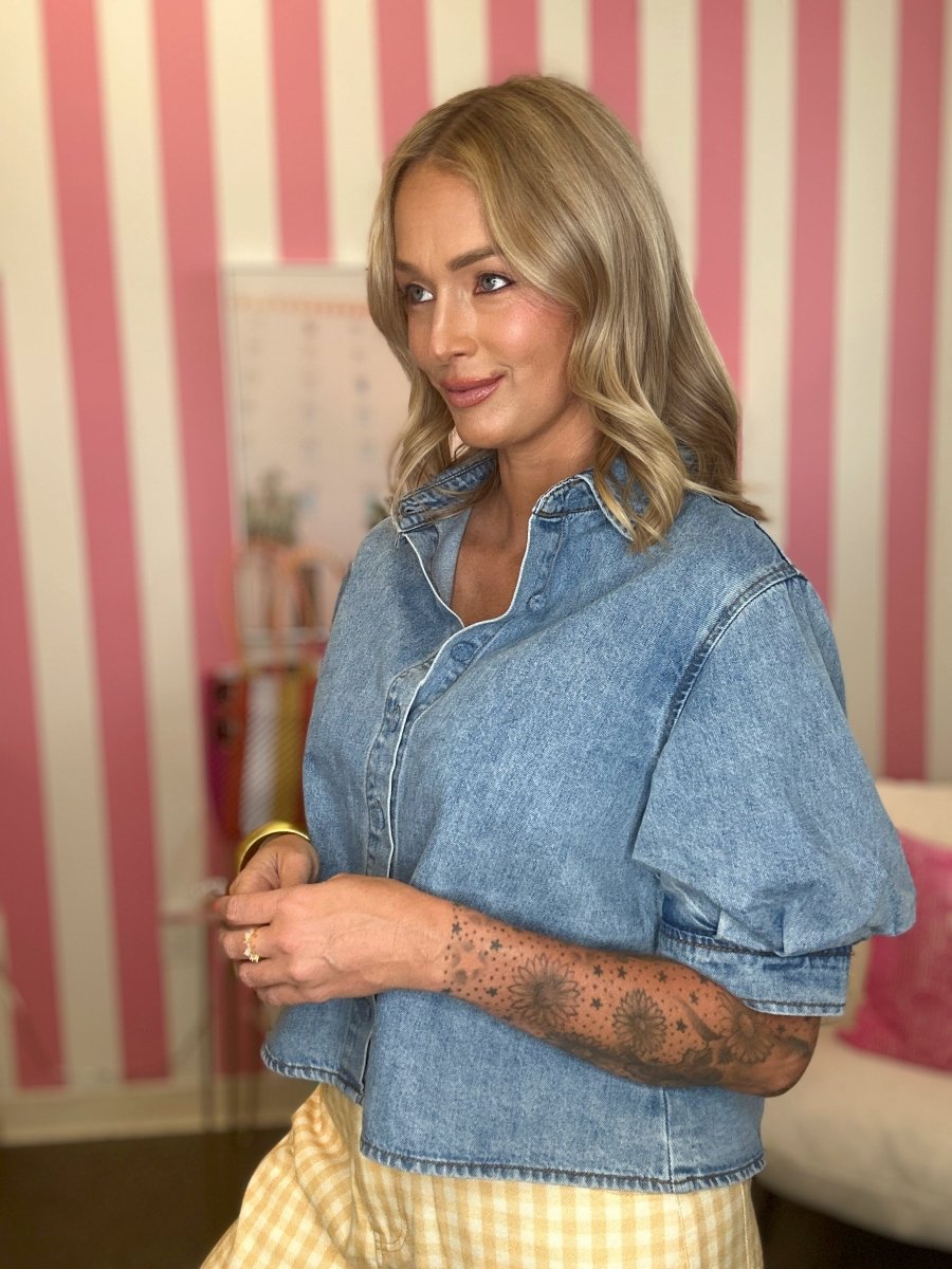 Woman wearing a denim shirt in a room with striped wallpaper