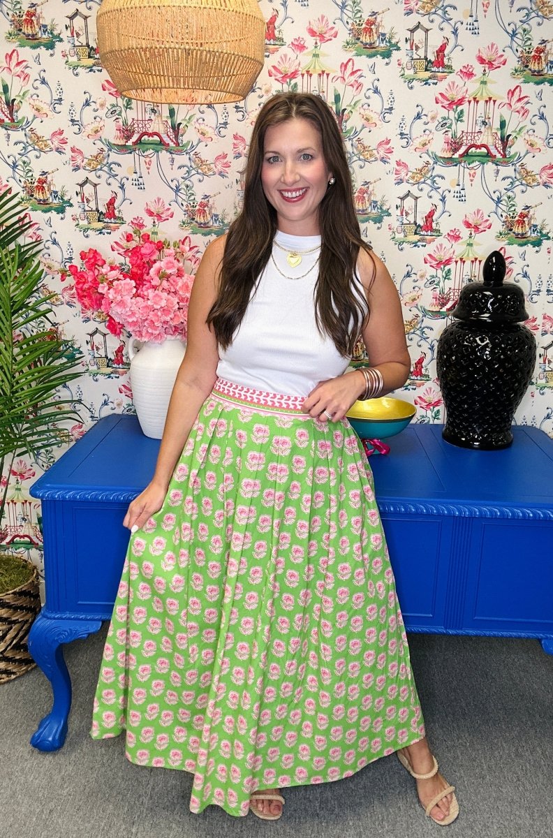 Woman in a green floral skirt standing in a room with colorful wallpaper and furniture.