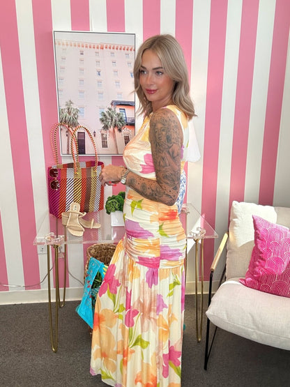 Woman in a colorful dress standing in a room with striped walls and furniture.