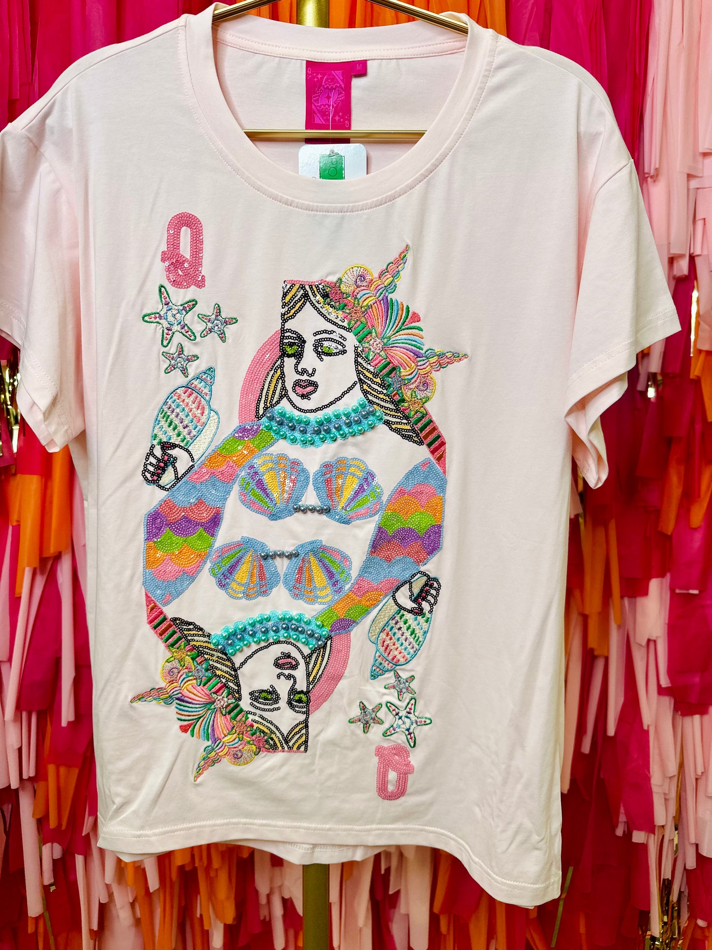 White t-shirt with colorful graphic design on a hanger against a vibrant background
