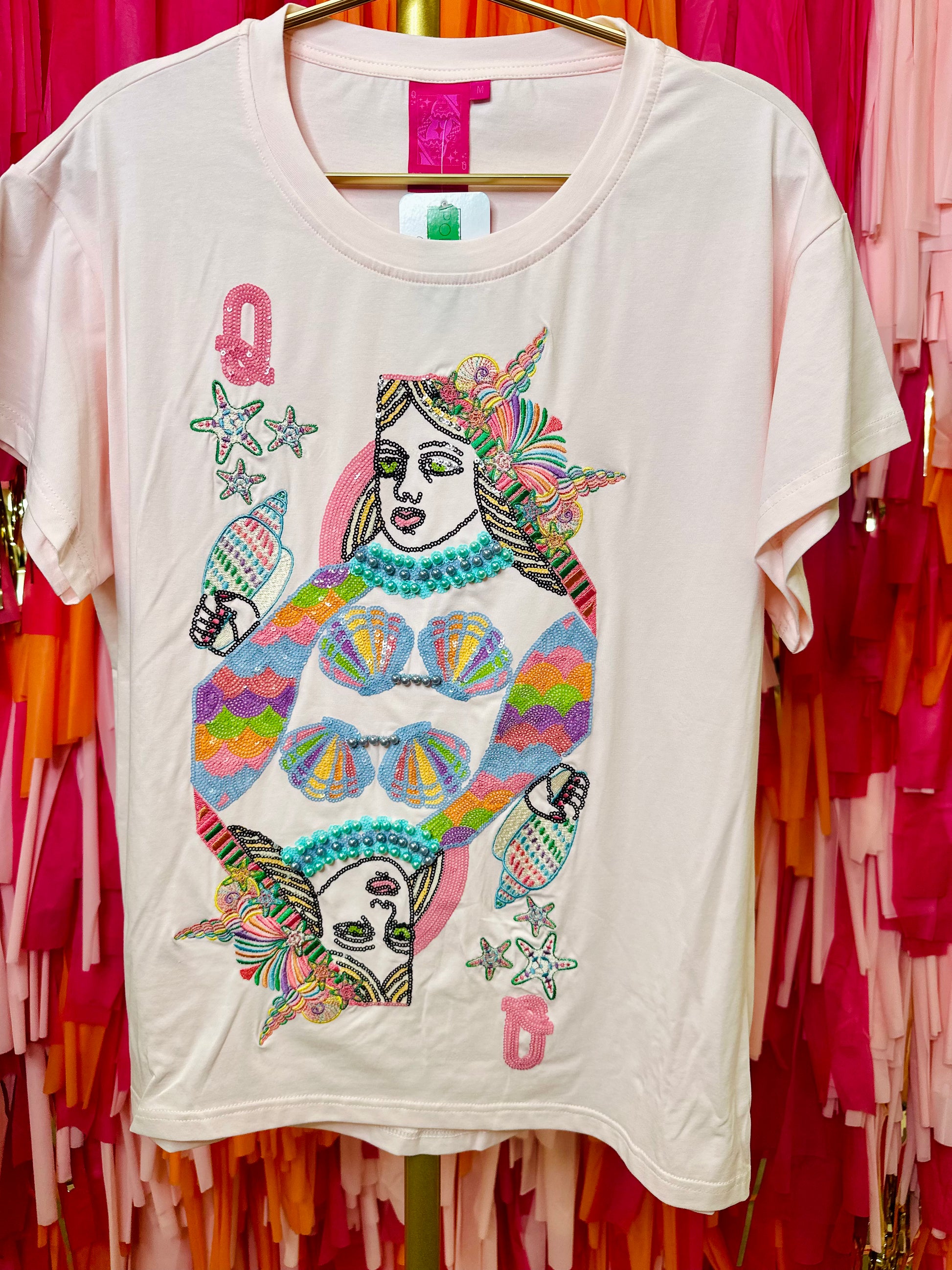 White t-shirt with colorful graphic design on a hanger against a vibrant background