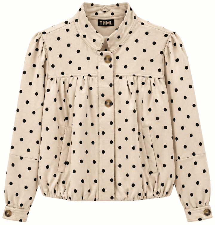 A beige long-sleeve button-up jacket with black polka dots, featuring a high collar, gathered waist, and decorative brown buttons, shown against a plain white background.