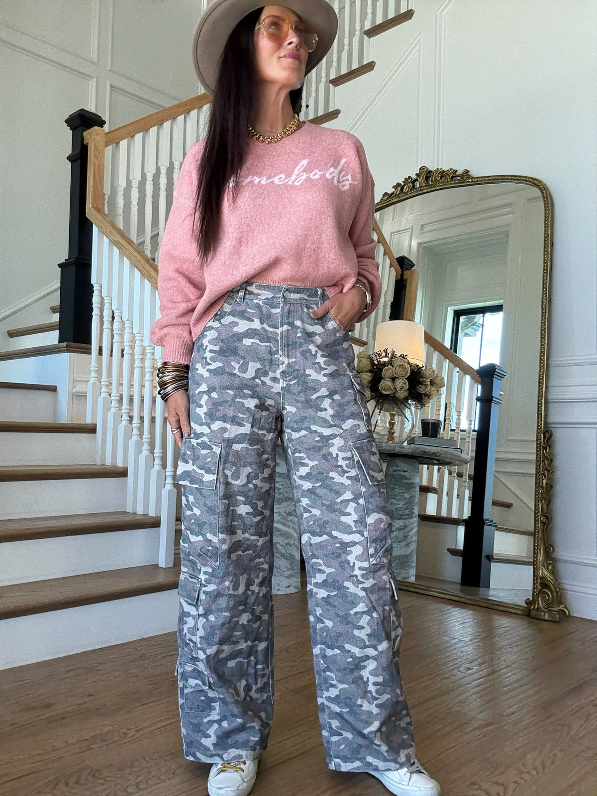woman standing in a pink sweater and camo cargo pants