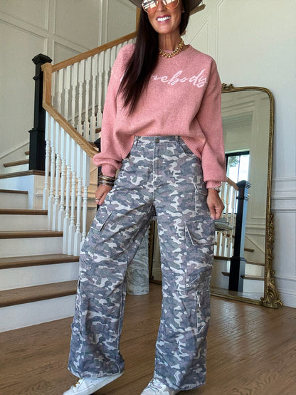 woman standing in a pink sweater and camo cargo pants