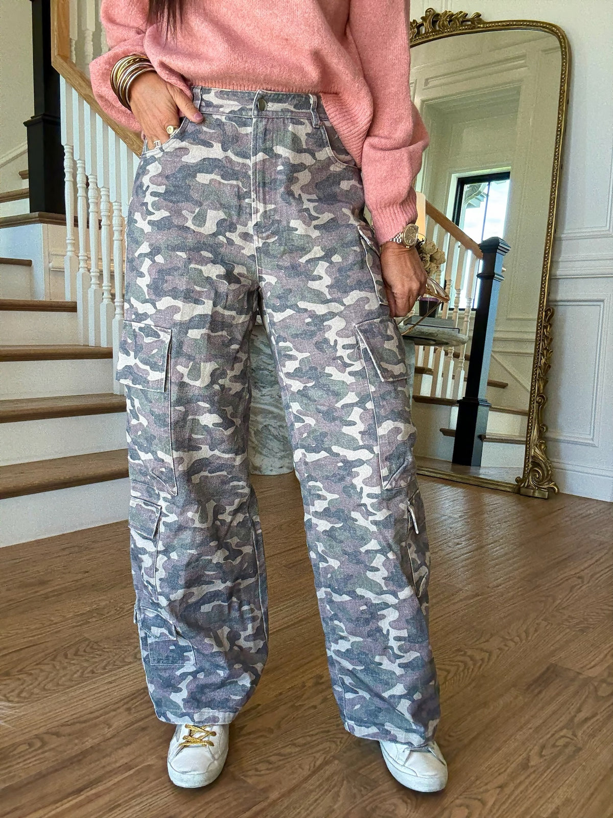 woman standing in a pink sweater and camo cargo pants