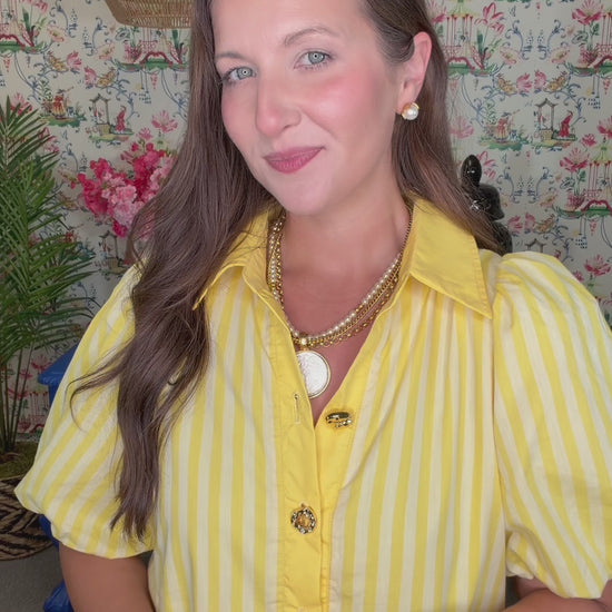 Woman in a yellow dress standing in front of a colorful wall with floral patterns.