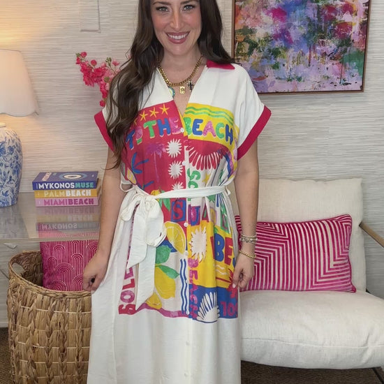 Woman wearing a colorful beach-themed dress in a living room setting