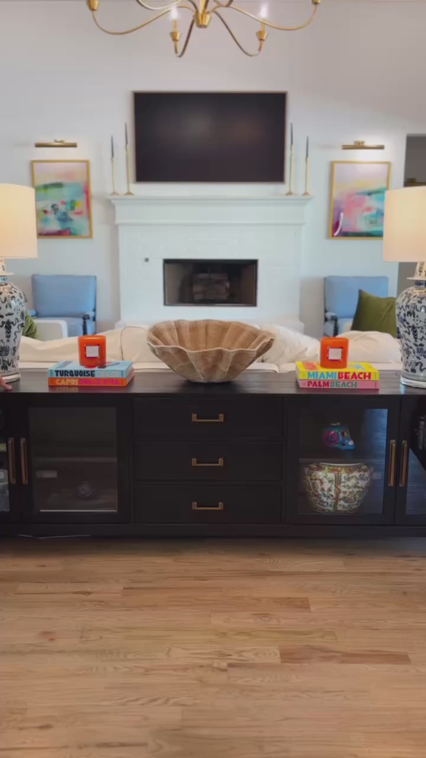two women in colorful towel wraps moving around the living room.