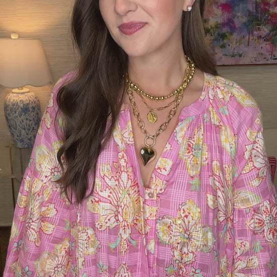 Woman in a pink floral dress standing in a room with a lamp and colorful painting.
