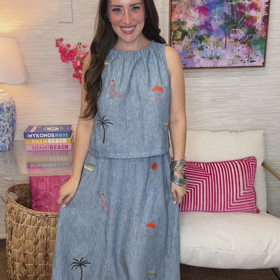 Woman wearing a blue dress with embroidery in a living room setting