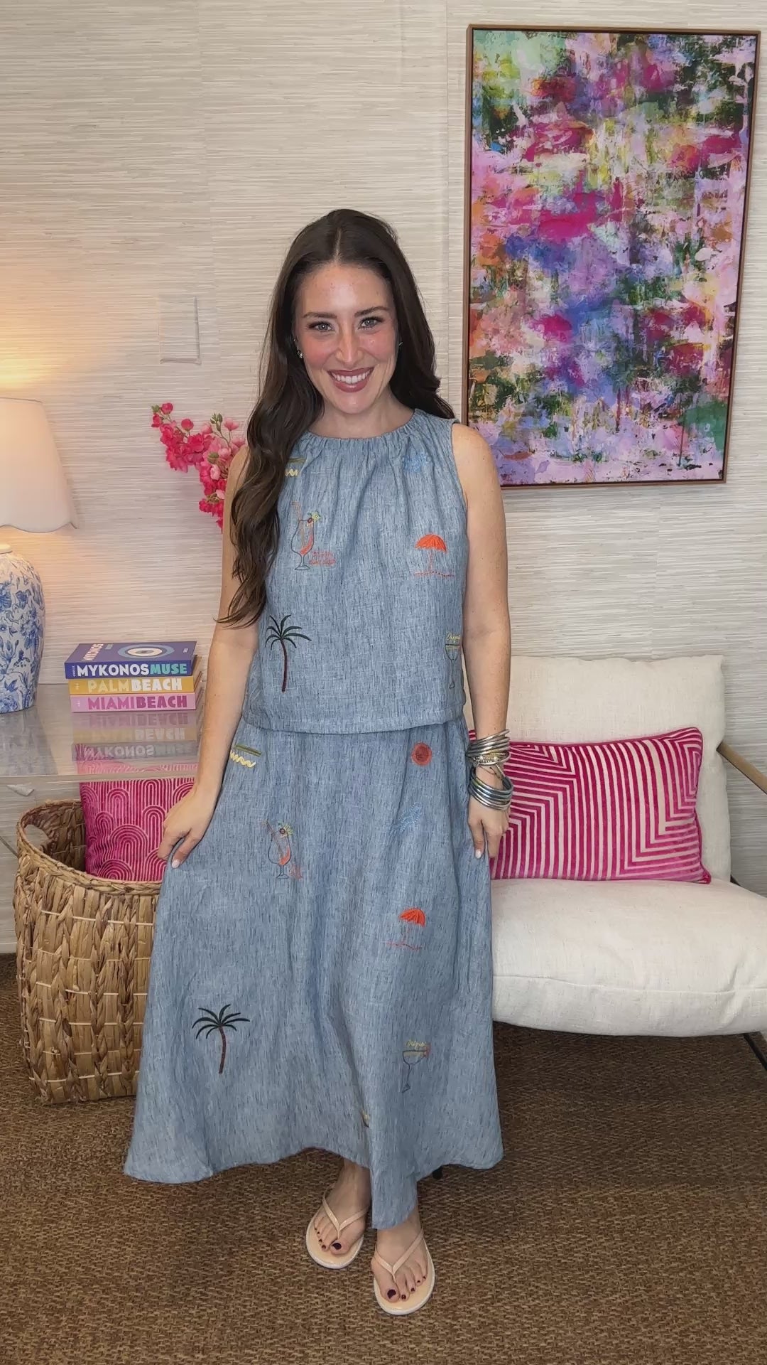 Woman wearing a blue dress with embroidery in a living room setting