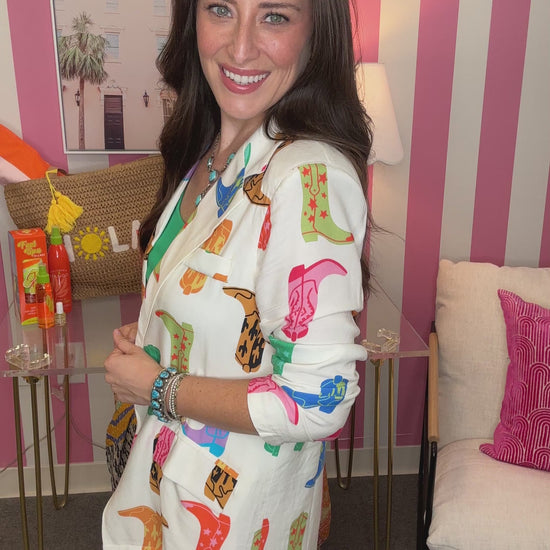 Woman wearing a colorful patterned jacket in a room with pink and white striped walls.