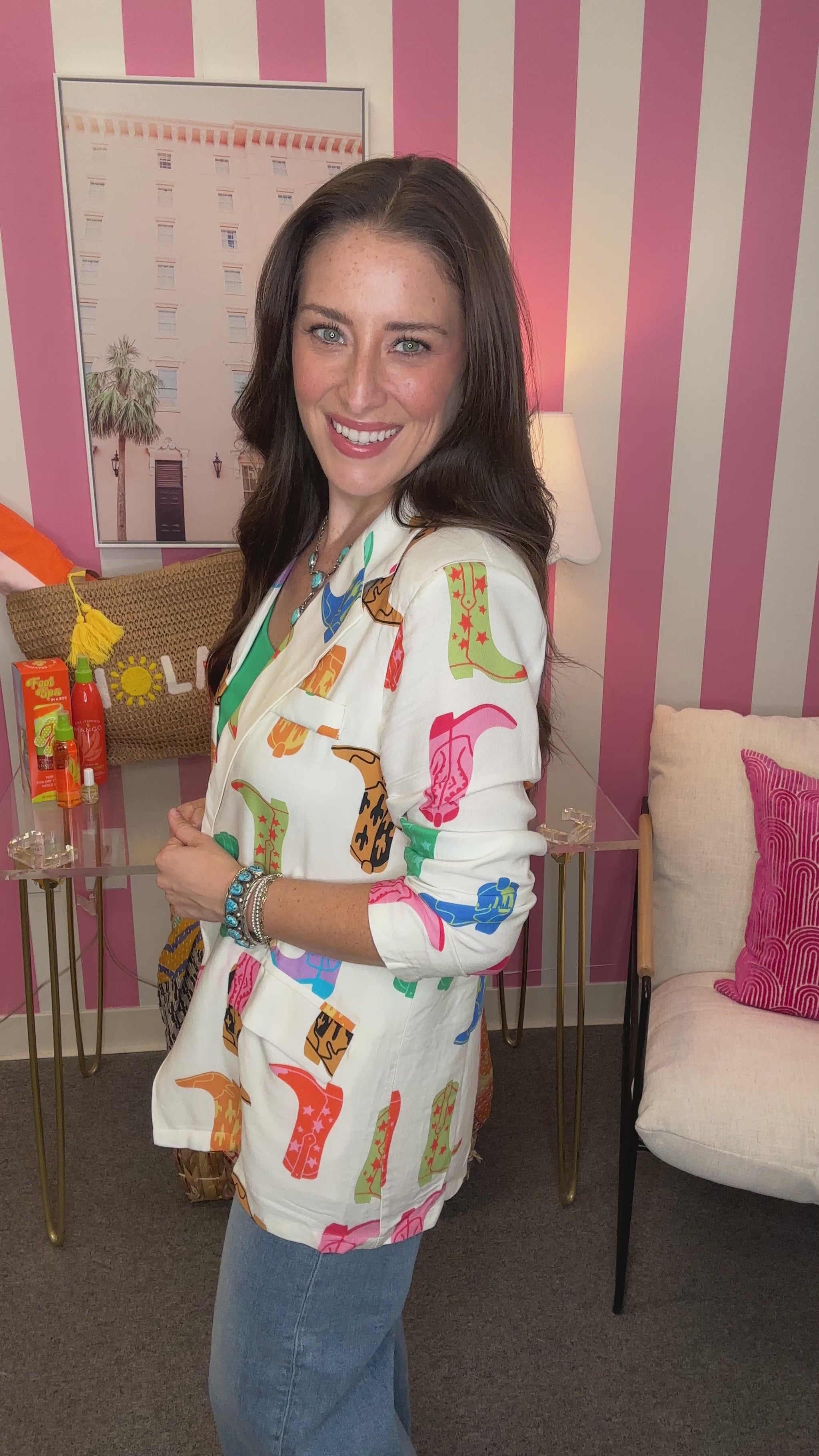 Woman wearing a colorful patterned jacket in a room with pink and white striped walls.
