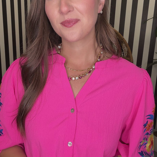 Woman wearing a bright pink blouse with floral sleeves indoors.
