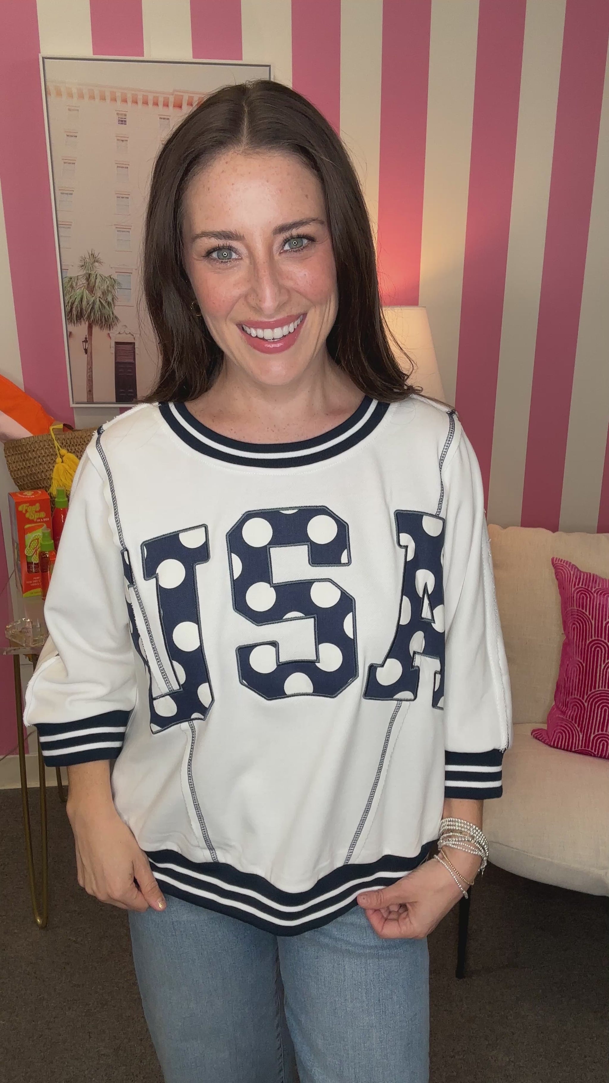 Woman wearing a white sweatshirt with 'USA' printed on it in a casual setting.