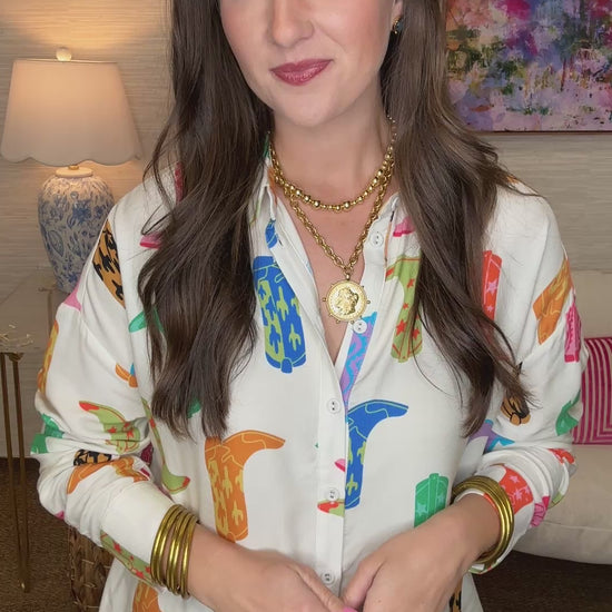 Woman wearing a colorful patterned shirt in a room with a lamp and painting in the background