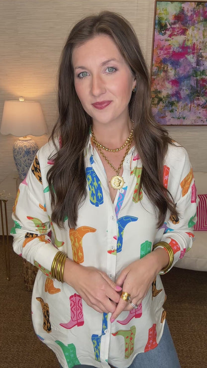 Woman wearing a colorful patterned shirt in a room with a lamp and painting in the background