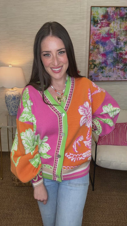Woman wearing a colorful floral-patterned jacket in a room with a lamp and painting.