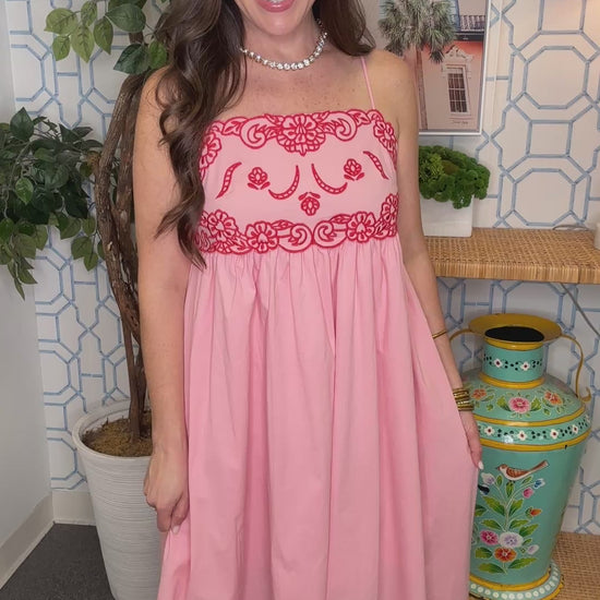 Woman in a pink dress standing in a room with decorative elements.