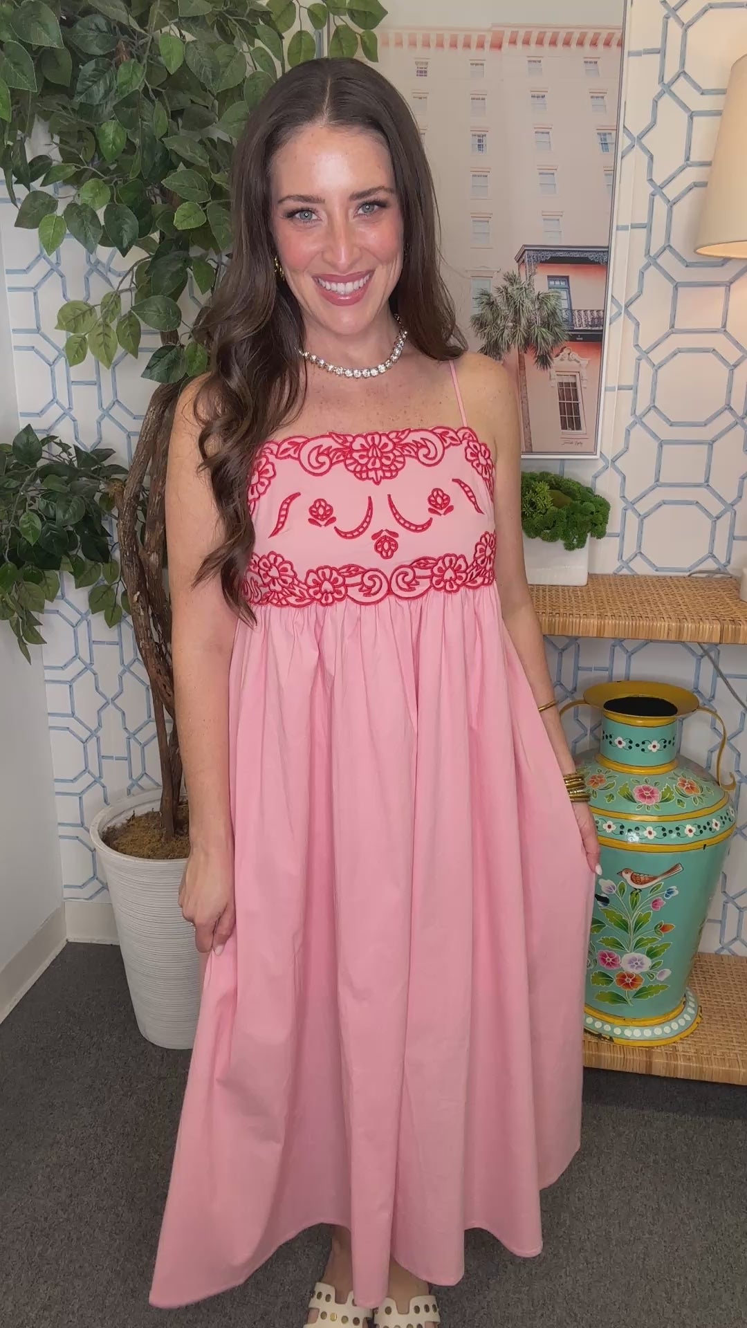 Woman in a pink dress standing in a room with decorative elements.
