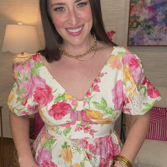 Woman wearing a floral top in a room with a colorful painting on the wall.