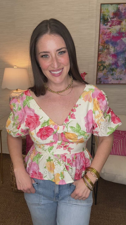Woman wearing a floral top in a room with a colorful painting on the wall.