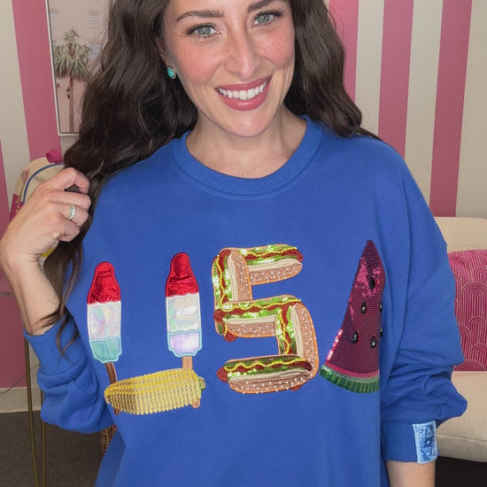 Woman wearing a blue sweatshirt with colorful letters in front of a striped background