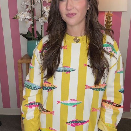 Woman wearing a yellow and white patterned sweater with a striped background