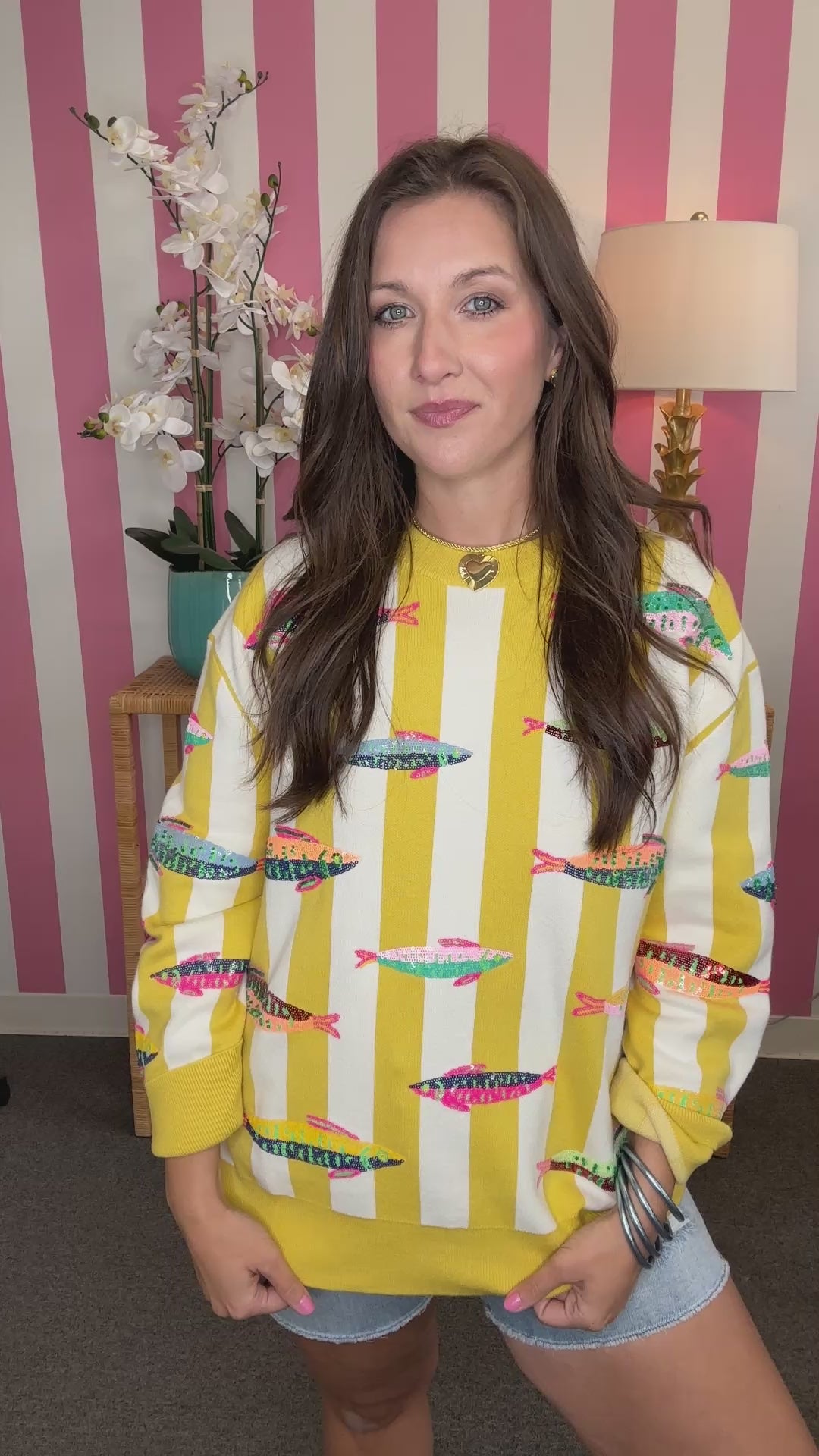 Woman wearing a yellow and white patterned sweater with a striped background