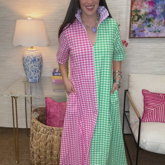 Woman in a colorful checkered dress standing in a room with decorative pillows and a lamp.