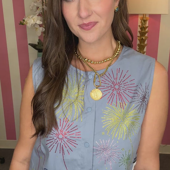 Woman wearing a blue sleeveless top and shorts with colorful patches in a room with striped walls.
