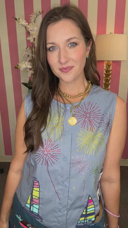 Woman wearing a blue sleeveless top and shorts with colorful patches in a room with striped walls.