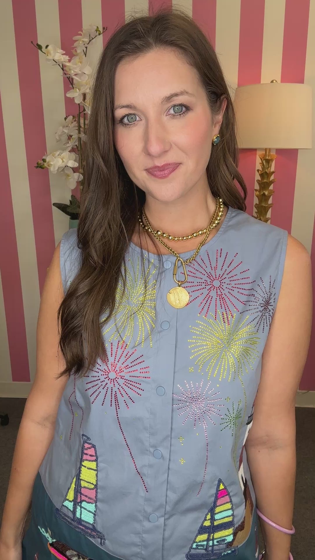 Woman wearing a blue sleeveless top and shorts with colorful patches in a room with striped walls.