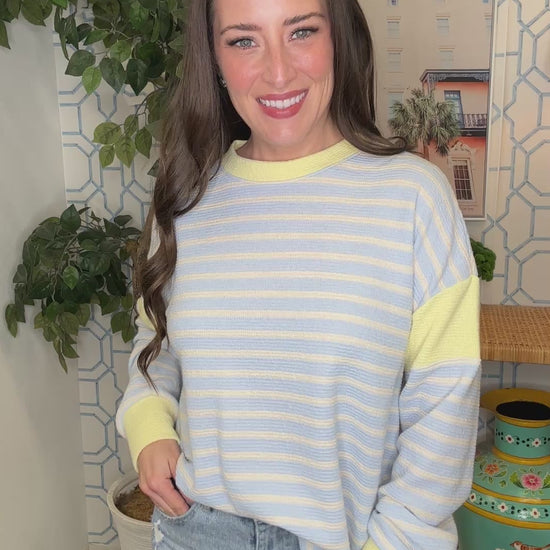 Woman wearing a blue and yellow striped sweater in a room with decorative elements.